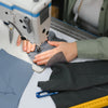 Seamstress hand-sewing GOTS-certified organic cotton fabric in a Fair Trade Certified facility